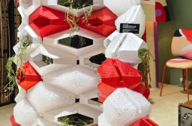 Uma divisória modular que une impressão 3D e biofilia. A estrutura geométrica, em vermelho e branco, funciona como uma colmeia high-tech, integrando plantas ao design. Uma solução funcional e escultural para dividir espaços.