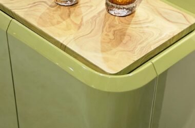 Design que une cor e textura. O aparador destaca-se pelas curvas suaves e pela laca brilhante em tom verde-oliva. O tampo rebaixado em madeira natural aquece a peça, enquanto os vidros âmbar texturizados adicionam um ponto de luz sofisticado.