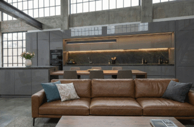 Cozinha planejada para apartamento pequeno estilo loft, com armários em laca cinza e bancada em Dekton, exemplificando o luxo compacto