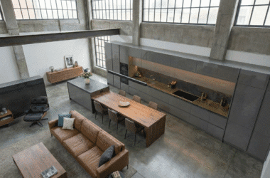 Cozinha planejada para apartamento pequeno estilo loft, com armários em laca cinza e bancada em Dekton, exemplificando o luxo compacto.