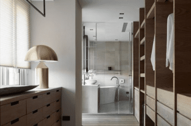 Detalhe de circulação em closet walk-in de suíte master com armários planejados sem portas, iluminação LED e nichos organizadores.