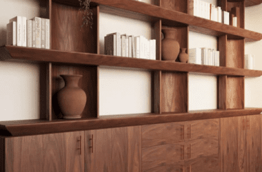 Estante sob medida branca do chão ao teto com escada metálica preta e iluminação de destaque, integrada ao ambiente de home office.