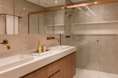 Banheiro de luxo com bancada extensa de mármore branco, duas cubas de apoio retangulares, dois espelhos redondos com iluminação LED atrás e torneiras pretas foscas saindo da parede