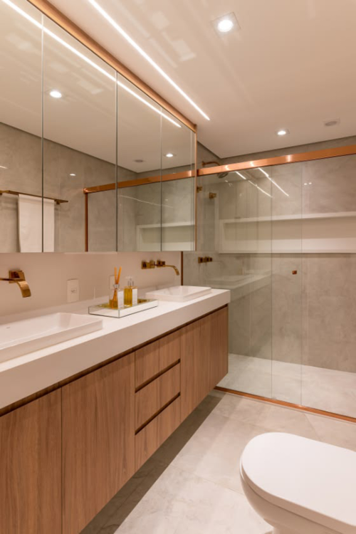 Banheiro de luxo com bancada extensa de mármore branco, duas cubas de apoio retangulares, dois espelhos redondos com iluminação LED atrás e torneiras pretas foscas saindo da parede