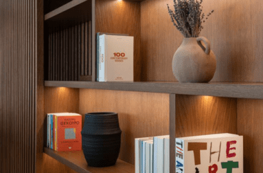 Detalhe técnico de prateleiras engrossadas em marcenaria de luxo para suportar o peso de livros em estante do chão ao teto.