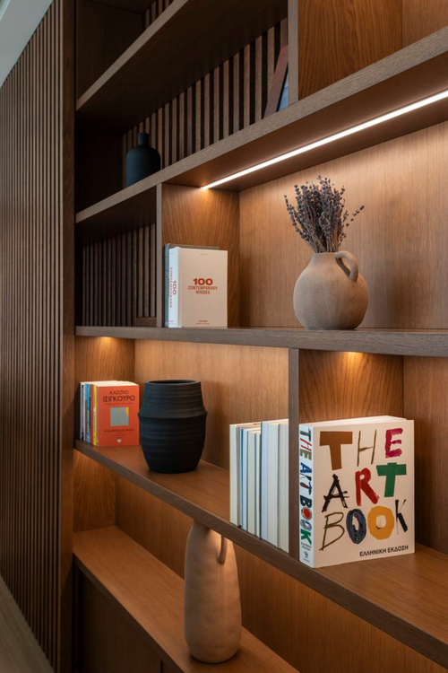 Detalhe técnico de prateleiras engrossadas em marcenaria de luxo para suportar o peso de livros em estante do chão ao teto.