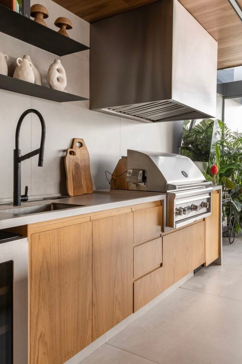 Churrasqueira de alto padrão revestida em porcelanato que imita aço corten, com iluminação interna e acabamento em inox.